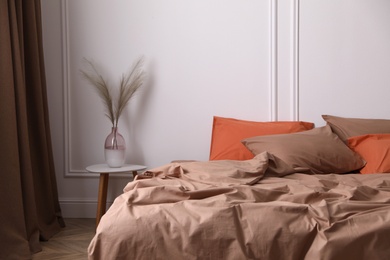 Bed with orange and brown linens in stylish room