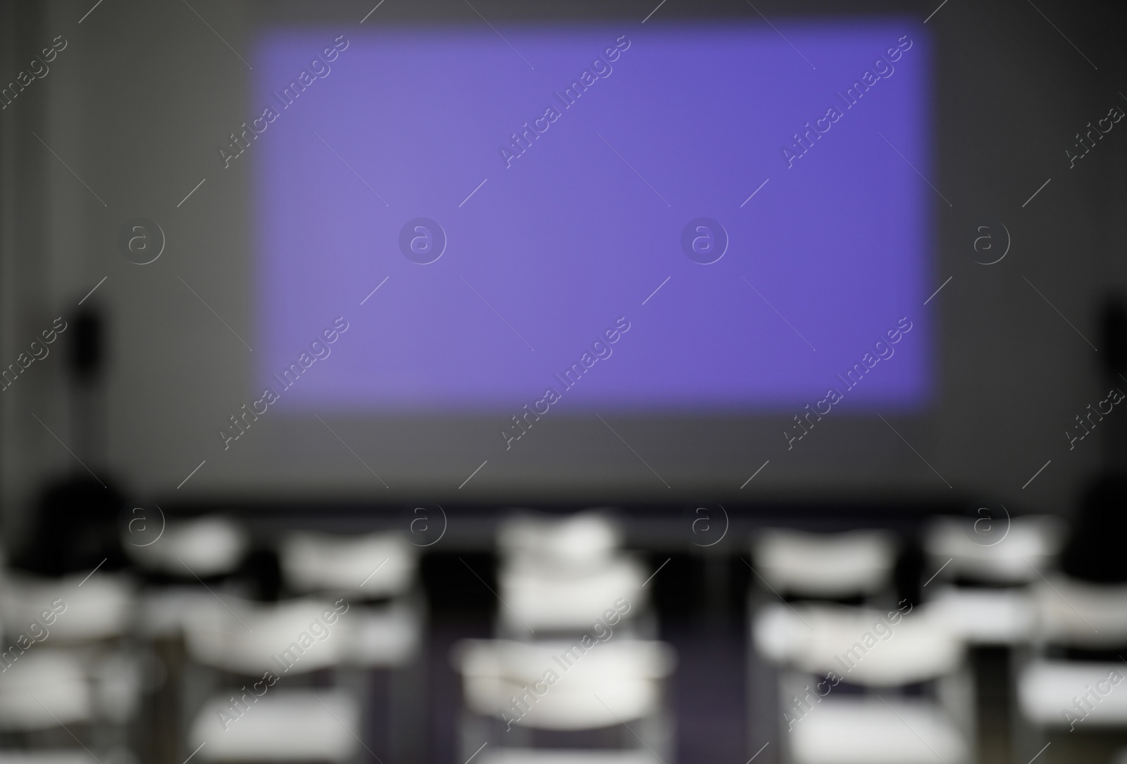 Photo of Blurred view of empty conference room with chairs and projector screen