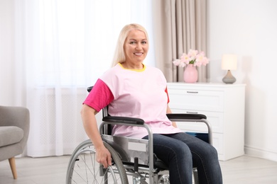 Mature woman sitting in wheelchair at home