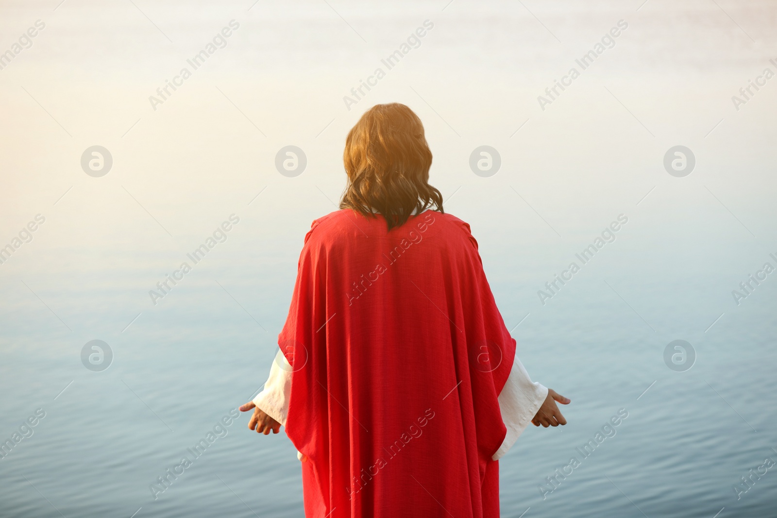 Photo of Jesus Christ near water outdoors, back view
