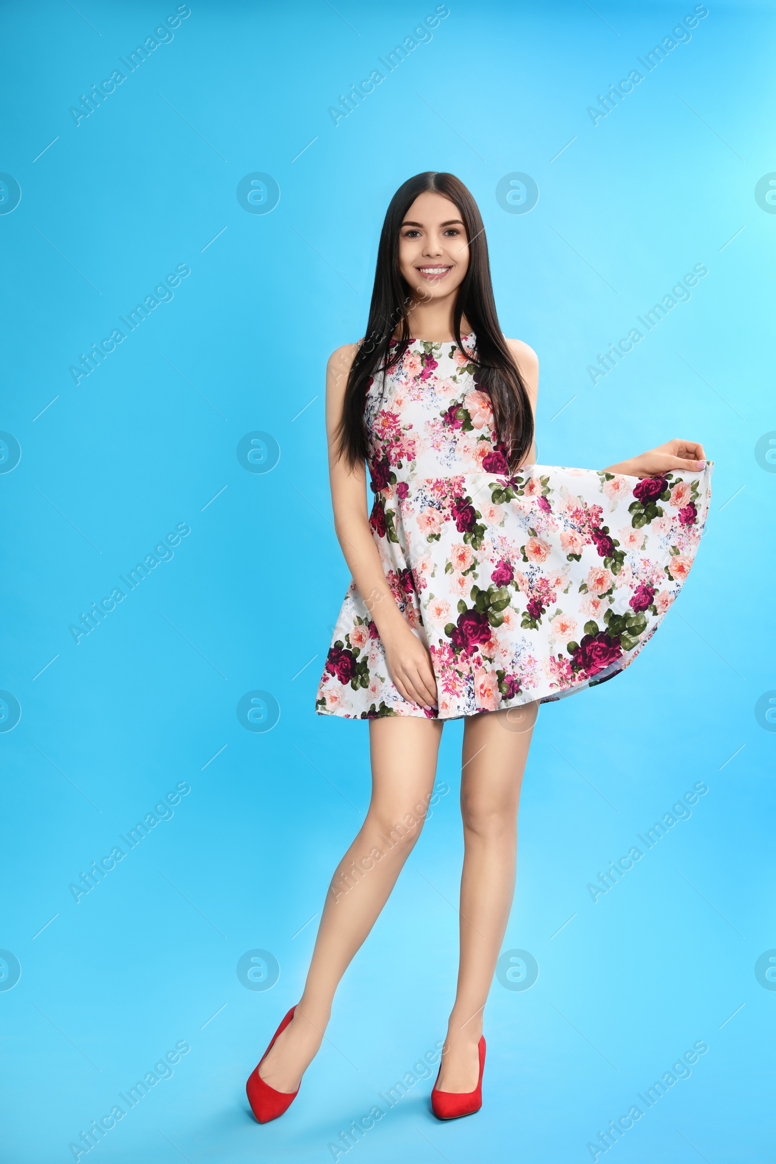 Photo of Young woman wearing floral print dress on light blue background