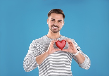 Man holding decorative heart on color background