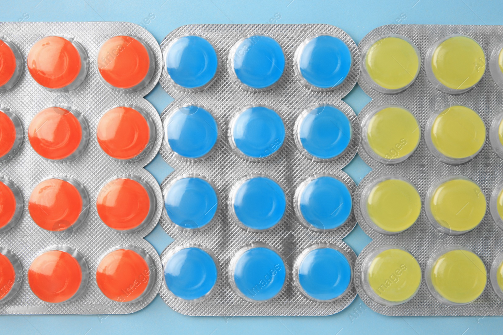 Photo of Blisters with cough drops on light blue background, flat lay