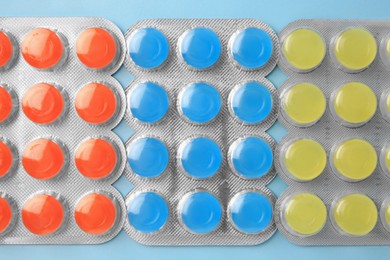 Photo of Blisters with cough drops on light blue background, flat lay