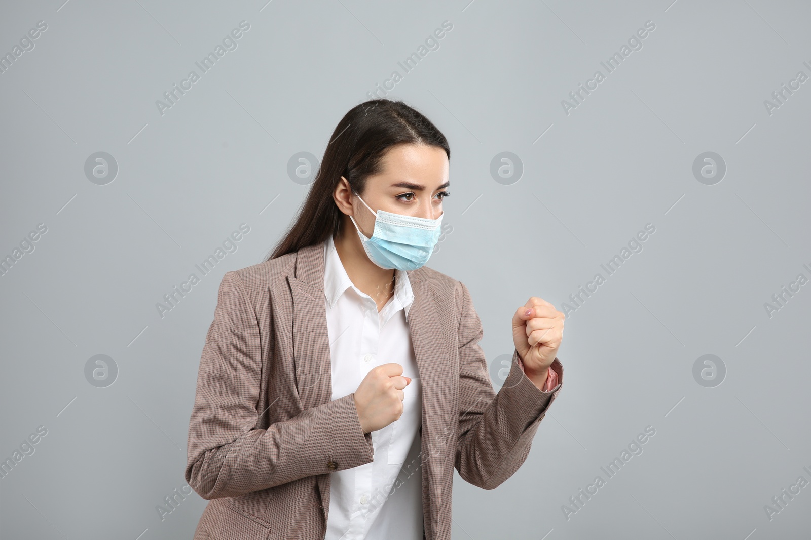 Photo of Businesswoman with protective mask in fighting pose on light grey background. Strong immunity concept