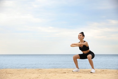 Young woman doing exercise on beach, space for text. Body training