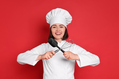 Photo of Happy confectioner holding whisk and spatula on red background