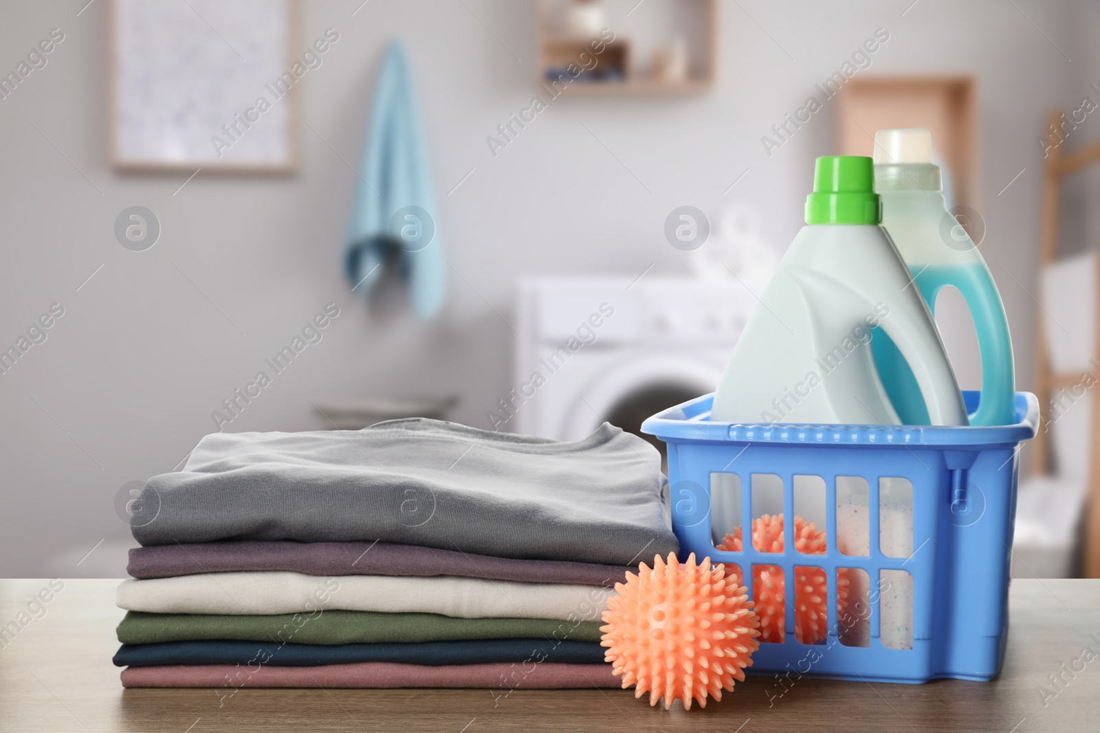 Image of Dryer balls, detergents and stacked clean clothes on wooden table in laundry room