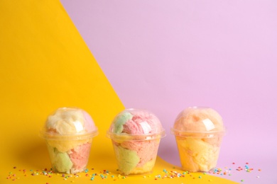 Photo of Yummy cotton candy in plastic cups on color background. Space for text