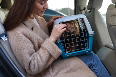 Woman with pet carrier travelling with her dog by car