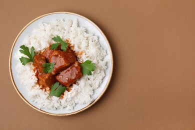 Photo of Delicious goulash with rice on brown background, top view. Space for text