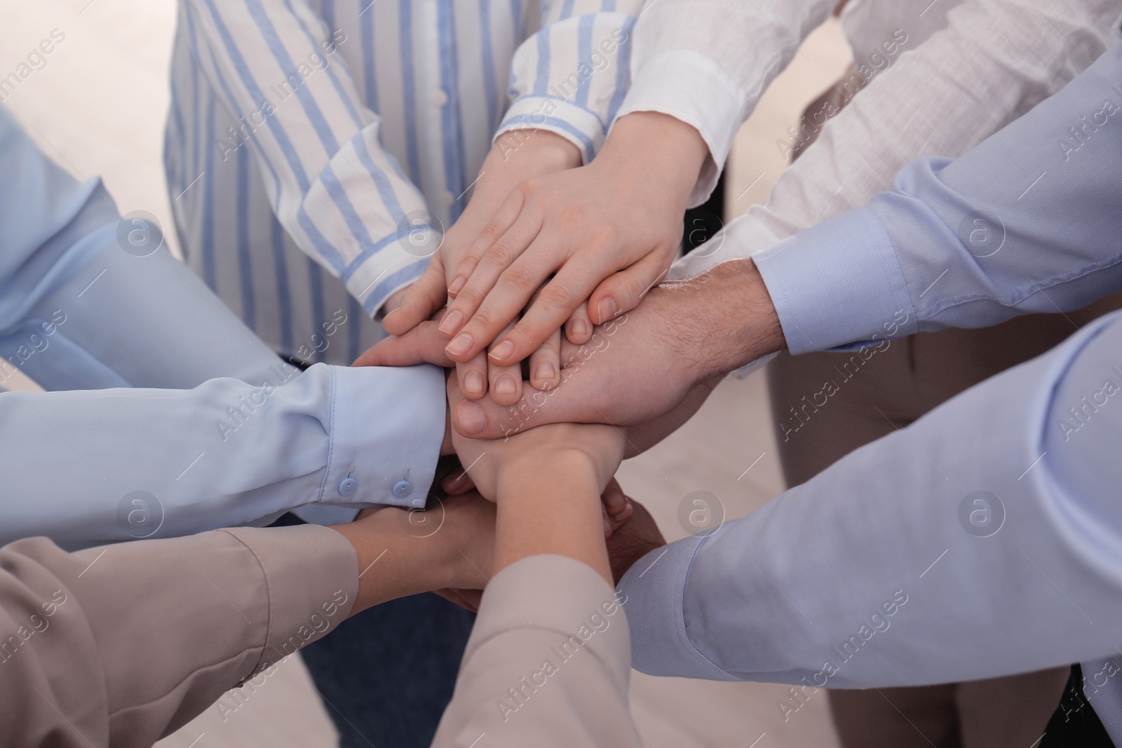 Photo of People holding hands together in office, closeup