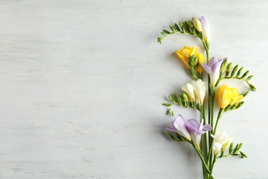 Photo of Beautiful fresh freesia flowers on wooden background, flat lay. Space for text