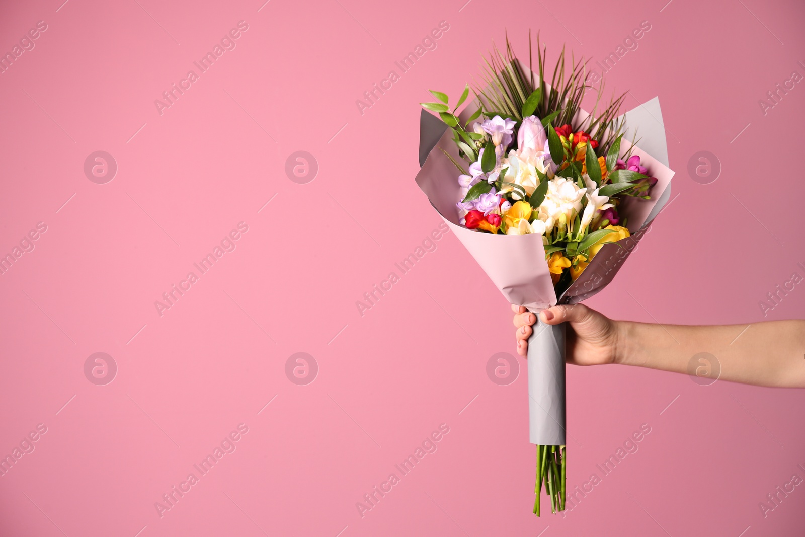 Photo of Woman with beautiful bouquet of freesia flowers on color background