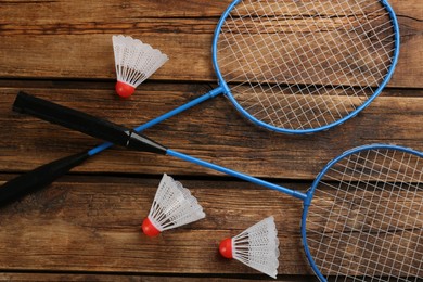 Photo of Rackets and shuttlecocks on wooden table, flat lay. Badminton equipment