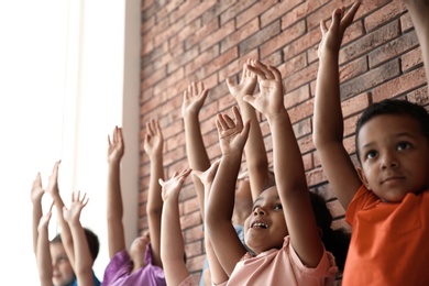 Photo of Little children raising hands together indoors. Unity concept