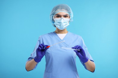 Laboratory testing. Doctor with cotton swab and tube on light blue background