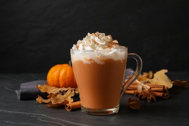Photo of Delicious pumpkin latte on black slate table, closeup