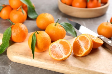 Fresh tangerines with green leaves on grey table