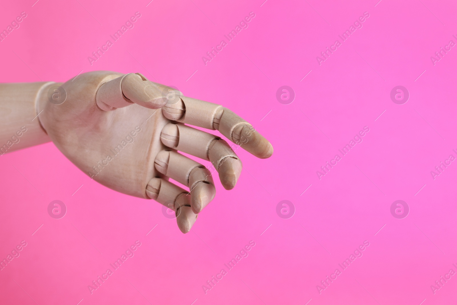 Photo of Wooden mannequin hand on pink background. Space for text