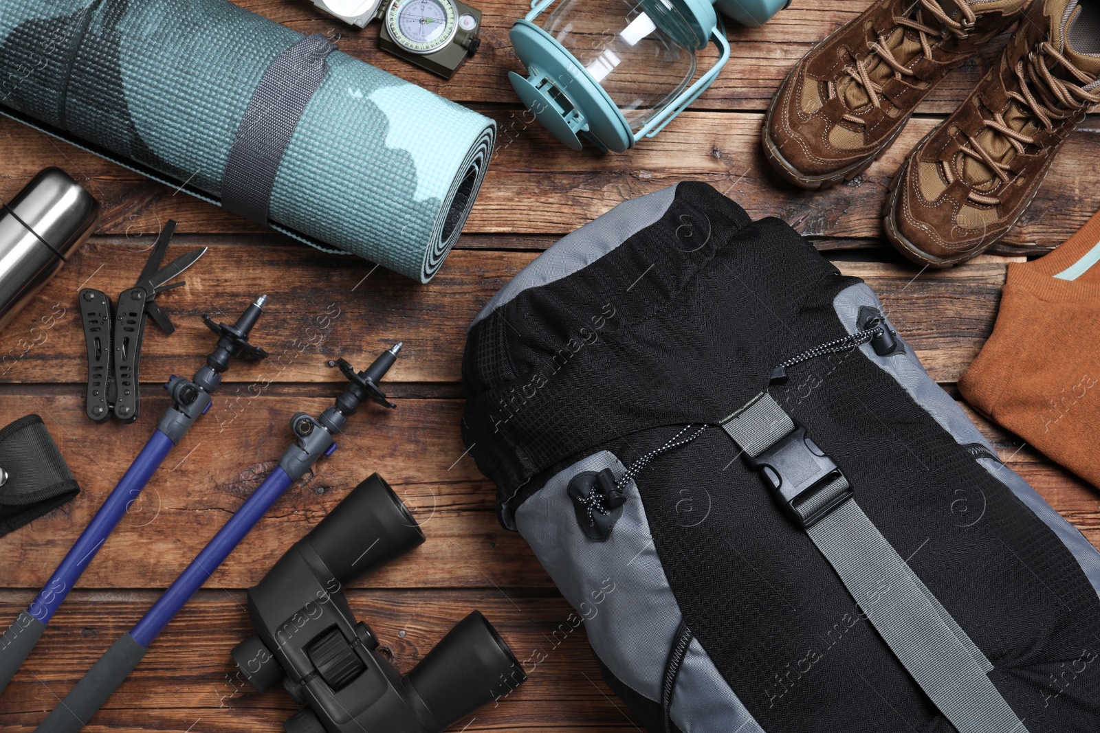 Photo of Flat lay composition with backpack and other different camping equipment for tourism on wooden background