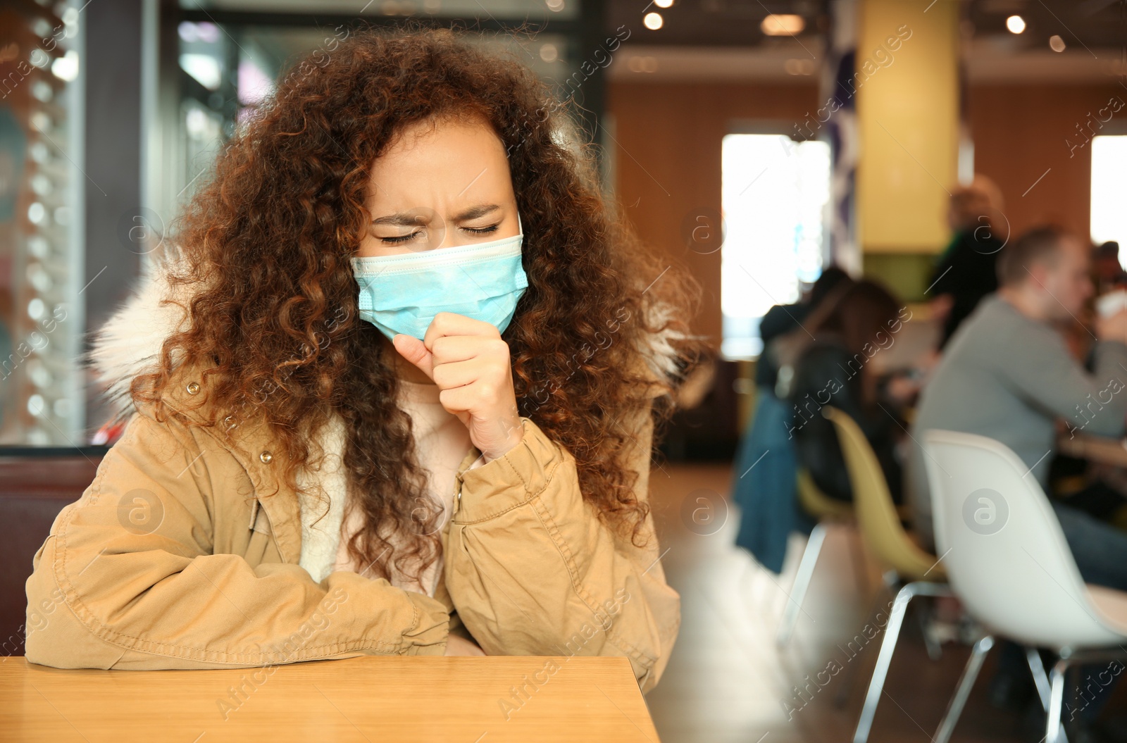 Photo of African-American woman with disposable mask in cafe. Virus protection