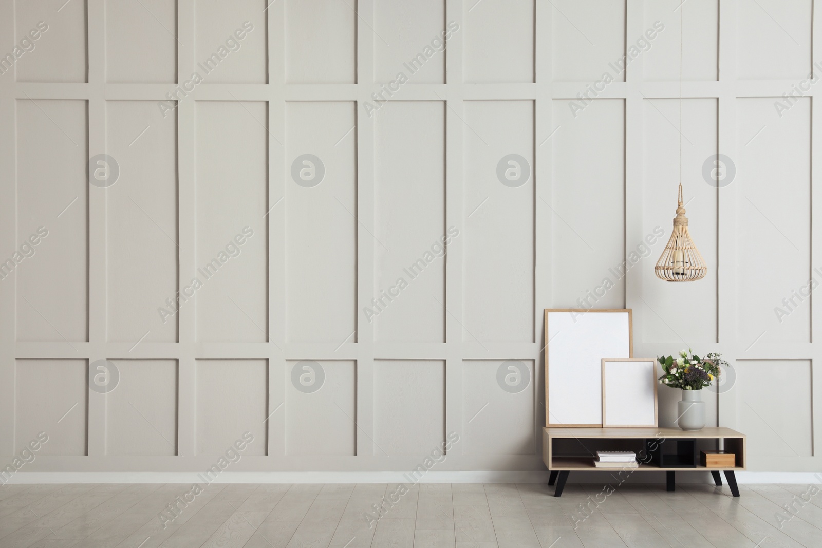 Photo of Simple room interior with console table, decor elements and empty wall. Space for design