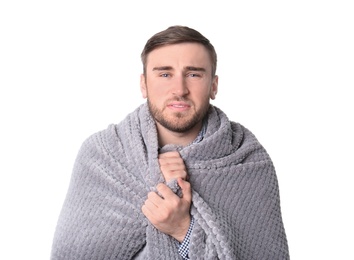 Young man with cold wrapped in blanket on white background