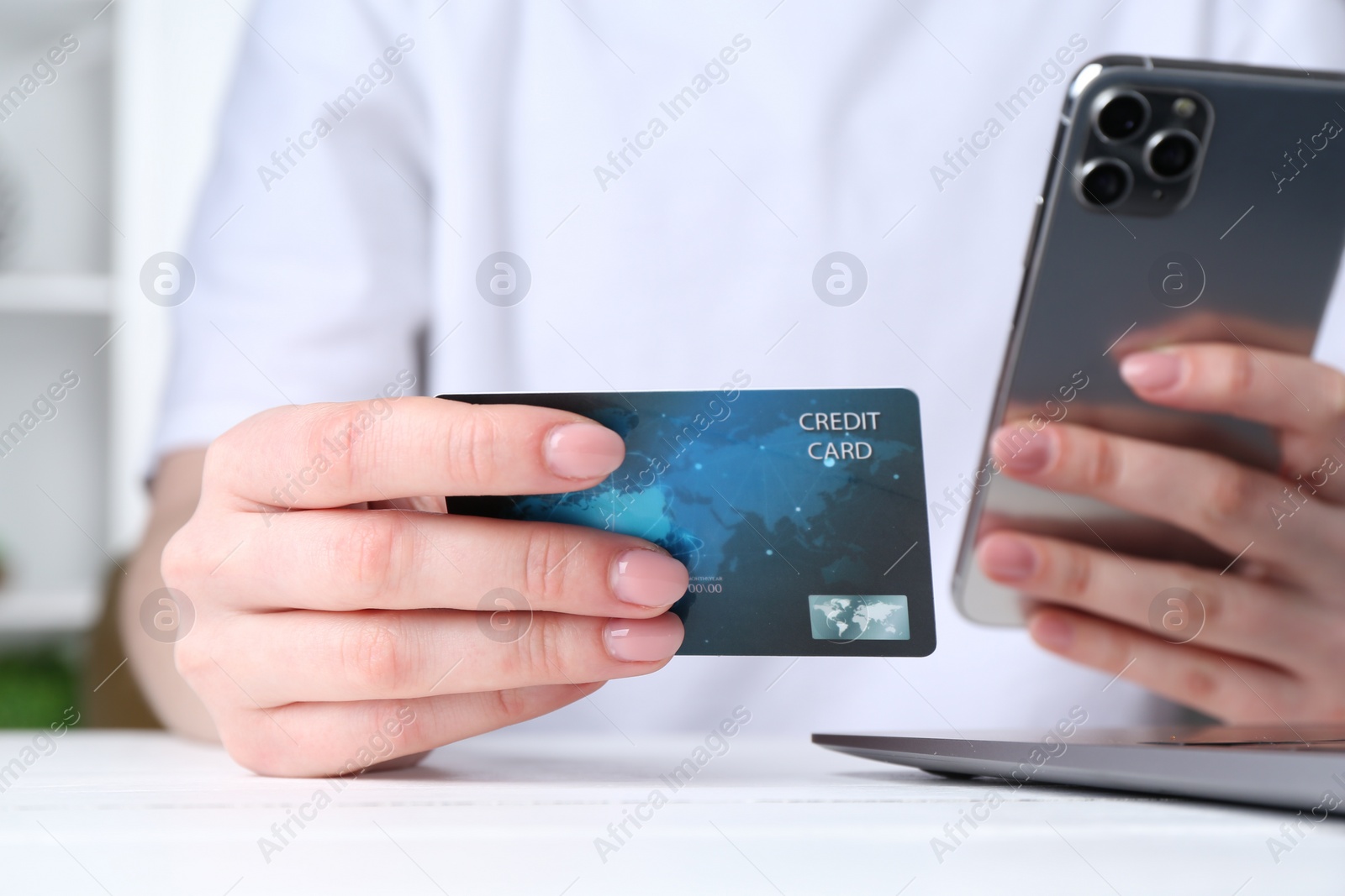 Photo of Online payment. Woman with laptop, smartphone and credit card at white table, closeup