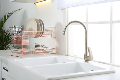 Clean dishes on drying rack in modern kitchen interior