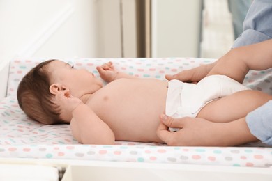 Mother changing baby's diaper on table at home, closeup