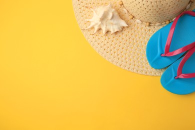 Photo of Flip flops, hat and seashell on yellow background, flat lay. Beach accessories