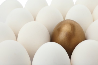 Photo of Golden egg among ordinary ones as background, closeup