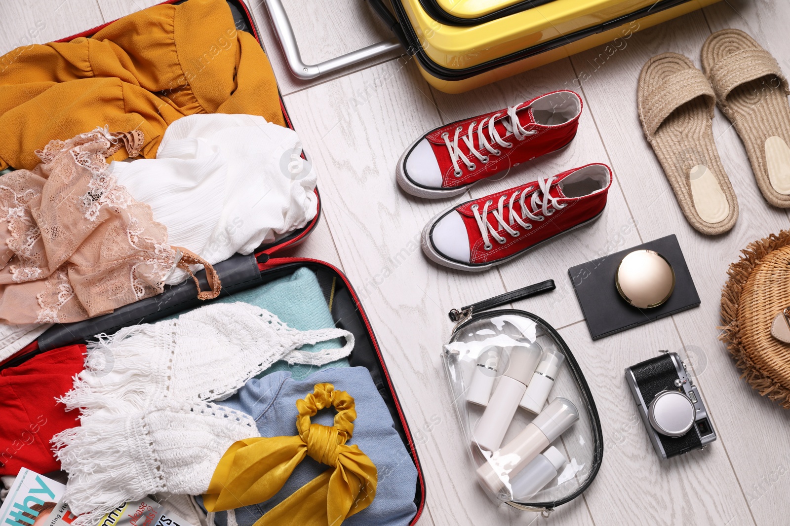 Photo of Suitcases with summer clothes, accessories and shoes on floor, above view