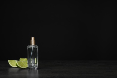 Photo of Perfume bottle and slices of citrus fruit on table against black background