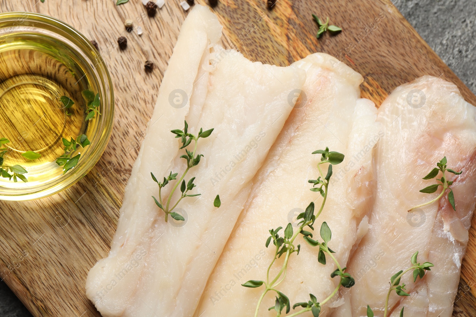 Photo of Raw cod fish, microgreens, oil and spices on grey textured table, top view