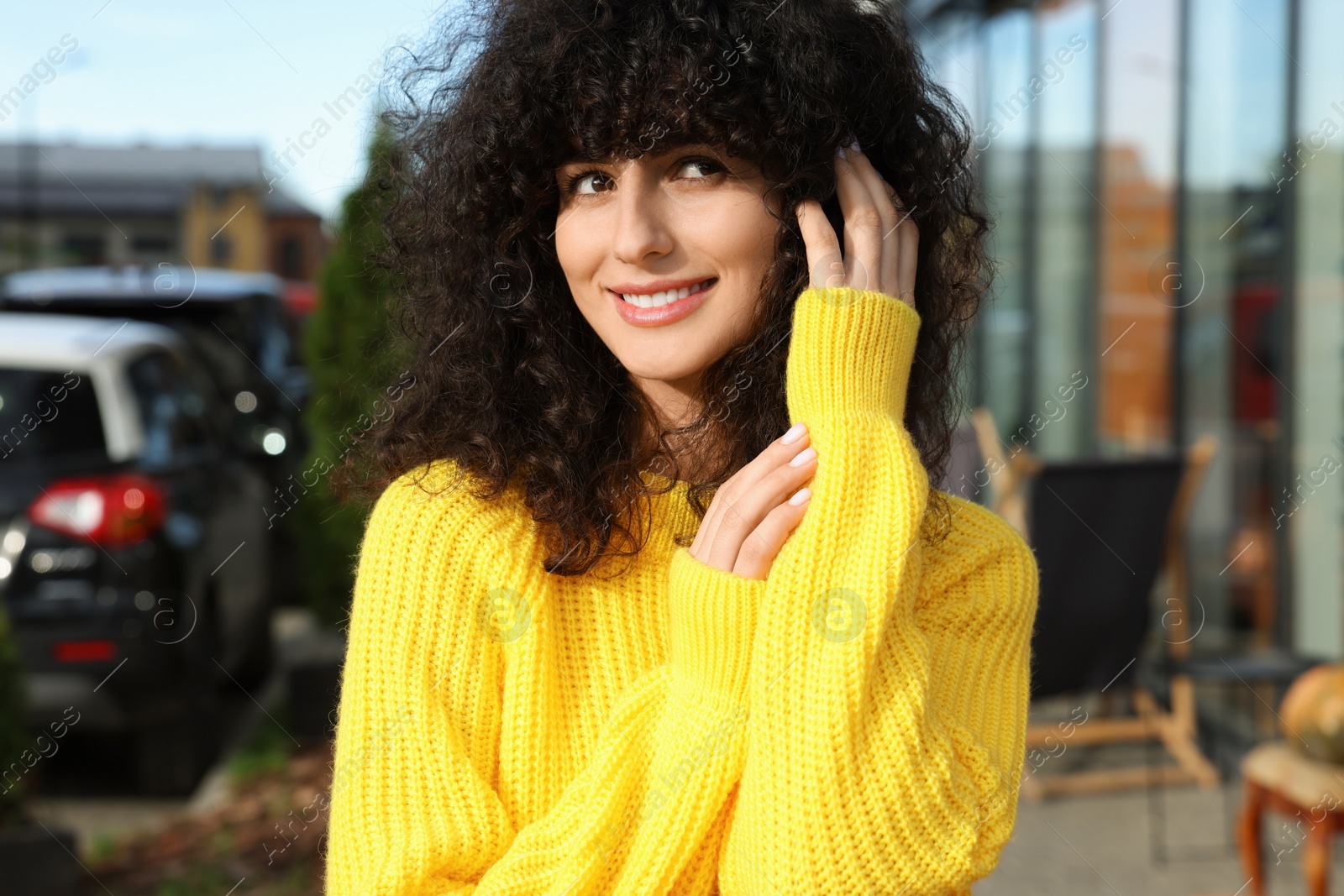 Photo of Happy young woman in stylish yellow sweater outdoors