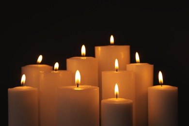 Burning candles on dark background. Symbol of sorrow