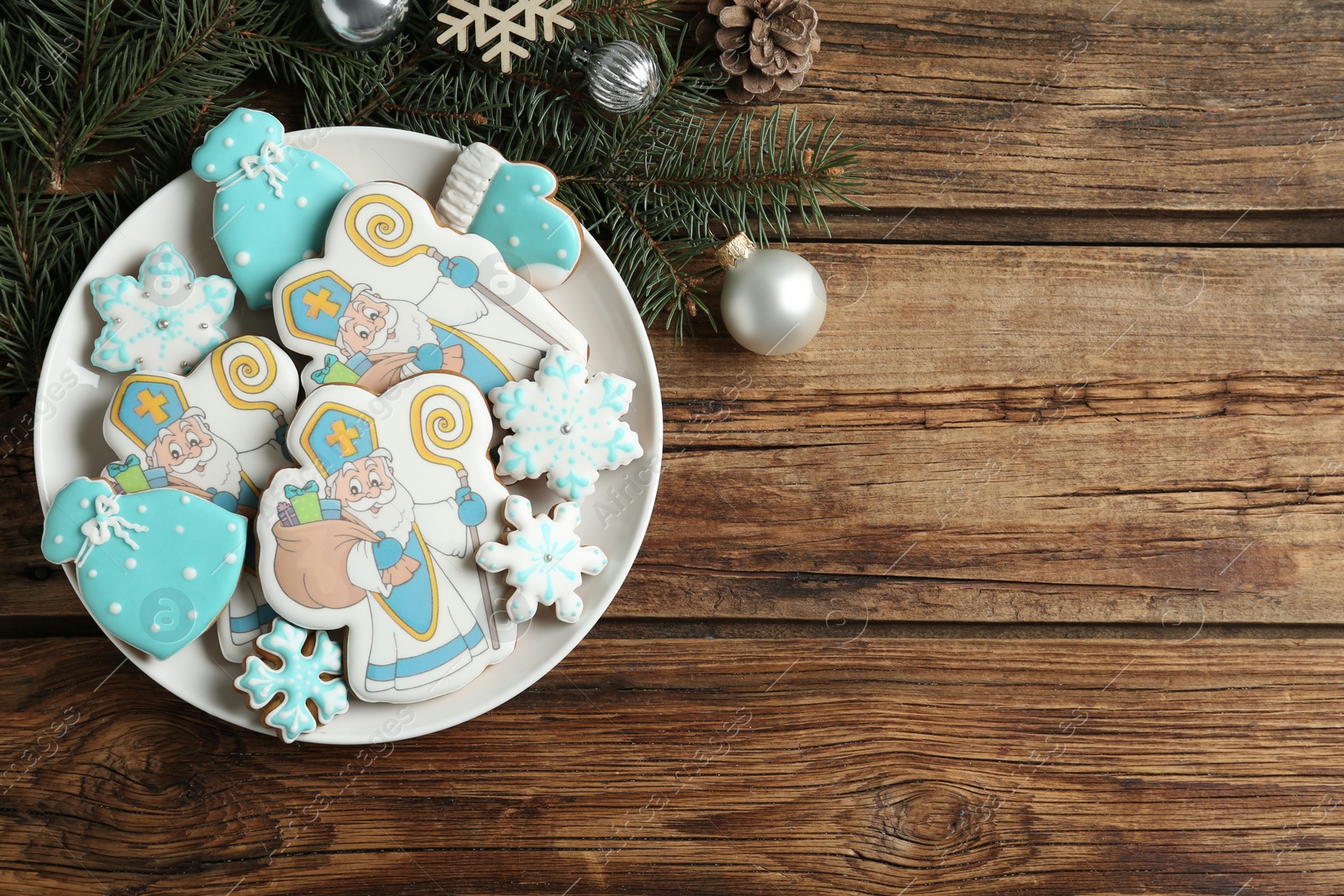 Photo of Tasty gingerbread cookies and festive decor on wooden table, flat lay with space for text. St. Nicholas Day celebration