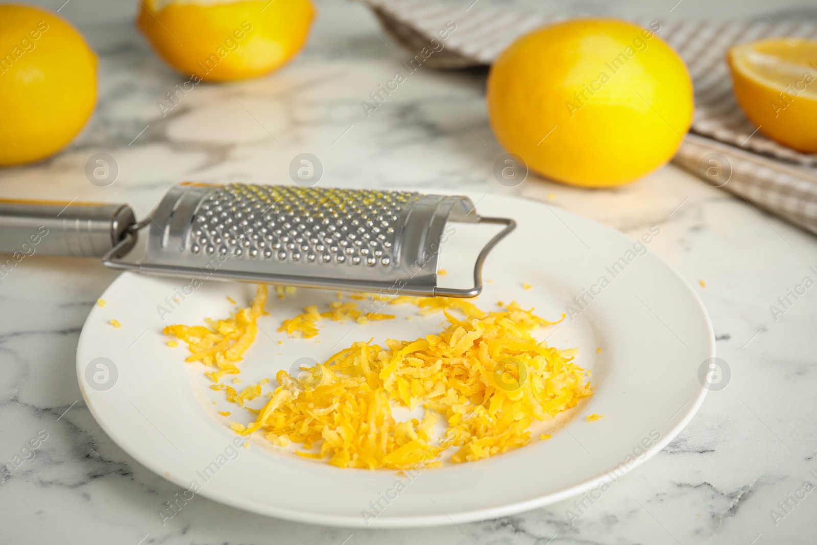 Photo of Lemon zest and fresh fruits on white marble table