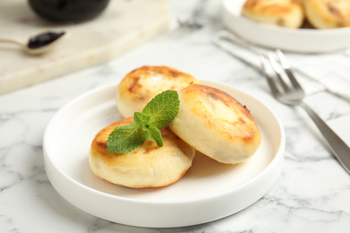 Photo of Delicious cottage cheese pancakes with mint on white marble table