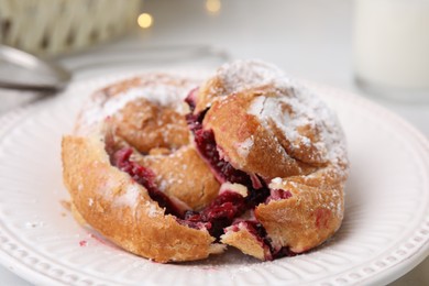 Photo of Delicious bun with sugar powder and berries on table, closeup
