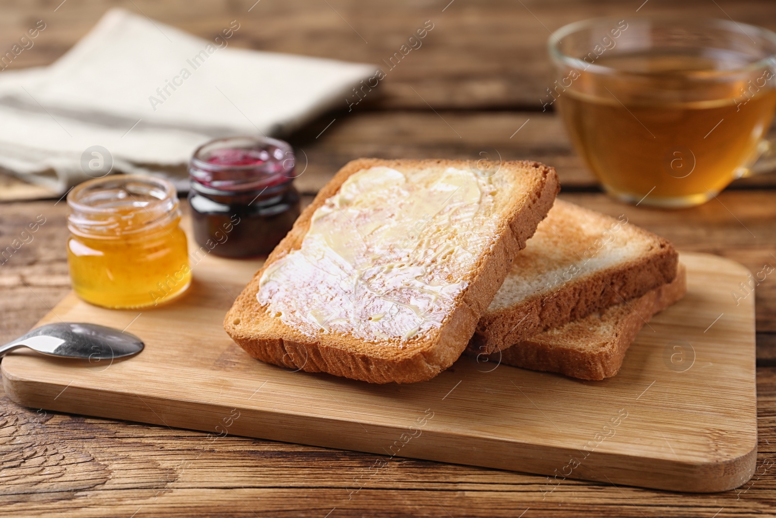 Photo of Delicious crispy toasts and jams on wooden table