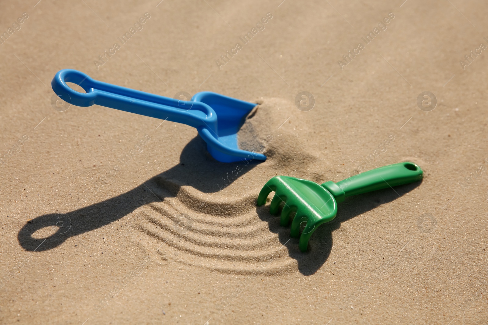 Photo of Bright plastic beach toys on sand. Outdoor play