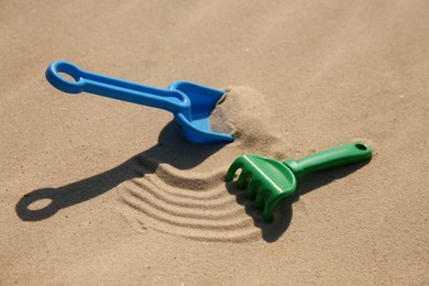 Photo of Bright plastic beach toys on sand. Outdoor play