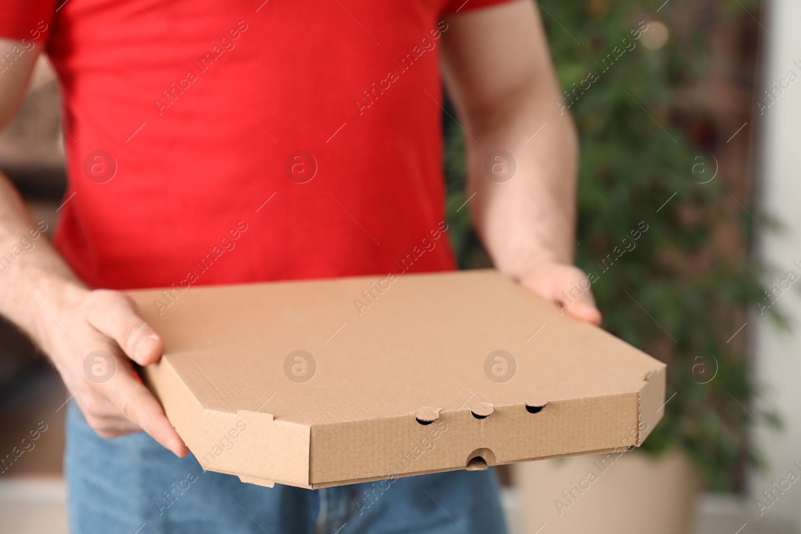 Photo of Courier with pizza box on blurred background, closeup. Space for text