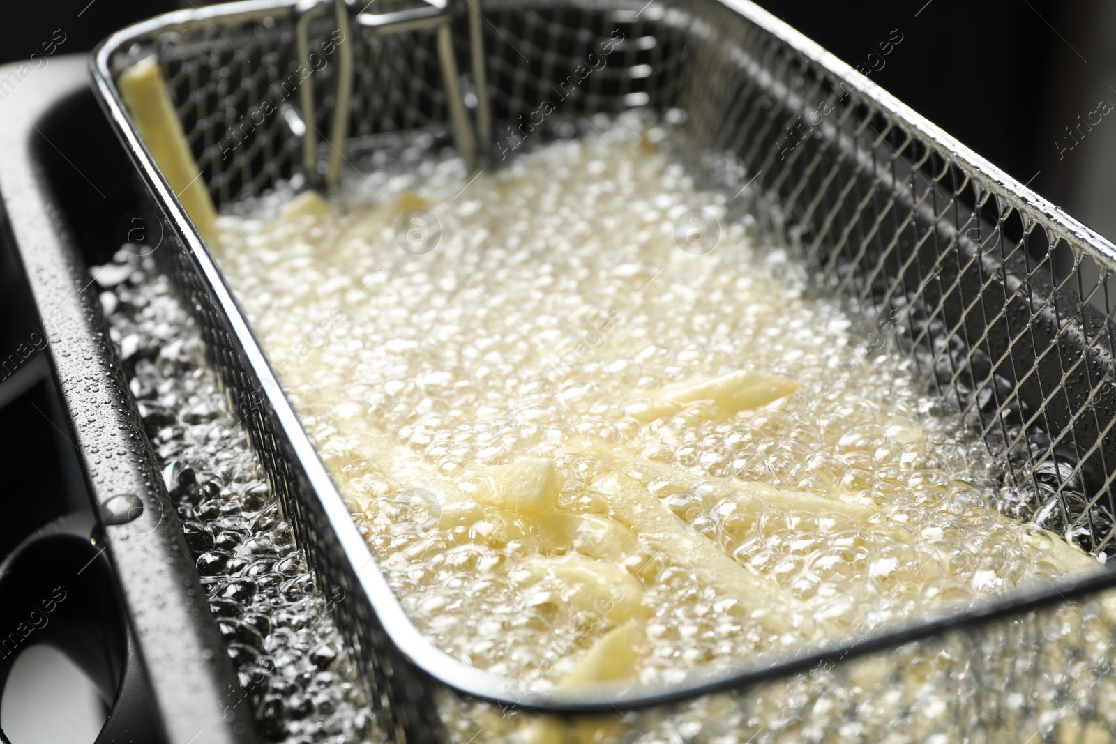 Photo of Cooking delicious french fries in hot oil, closeup