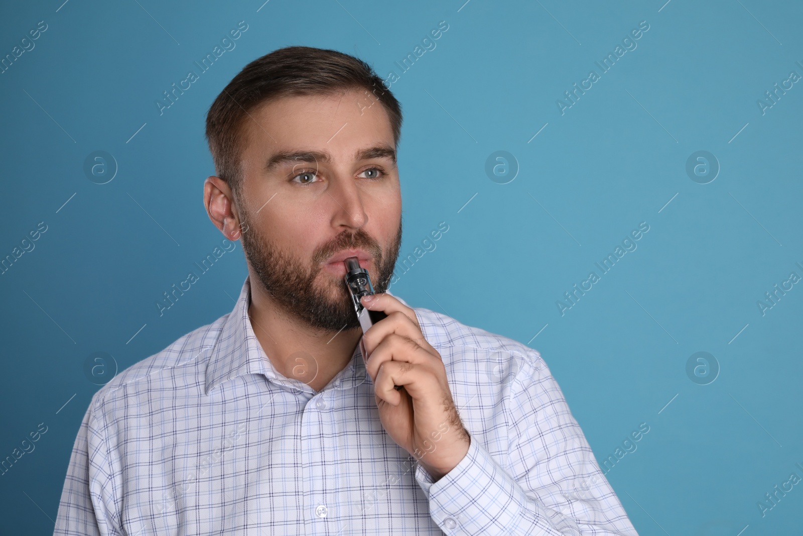 Photo of Man using electronic cigarette on light blue background. Space for text