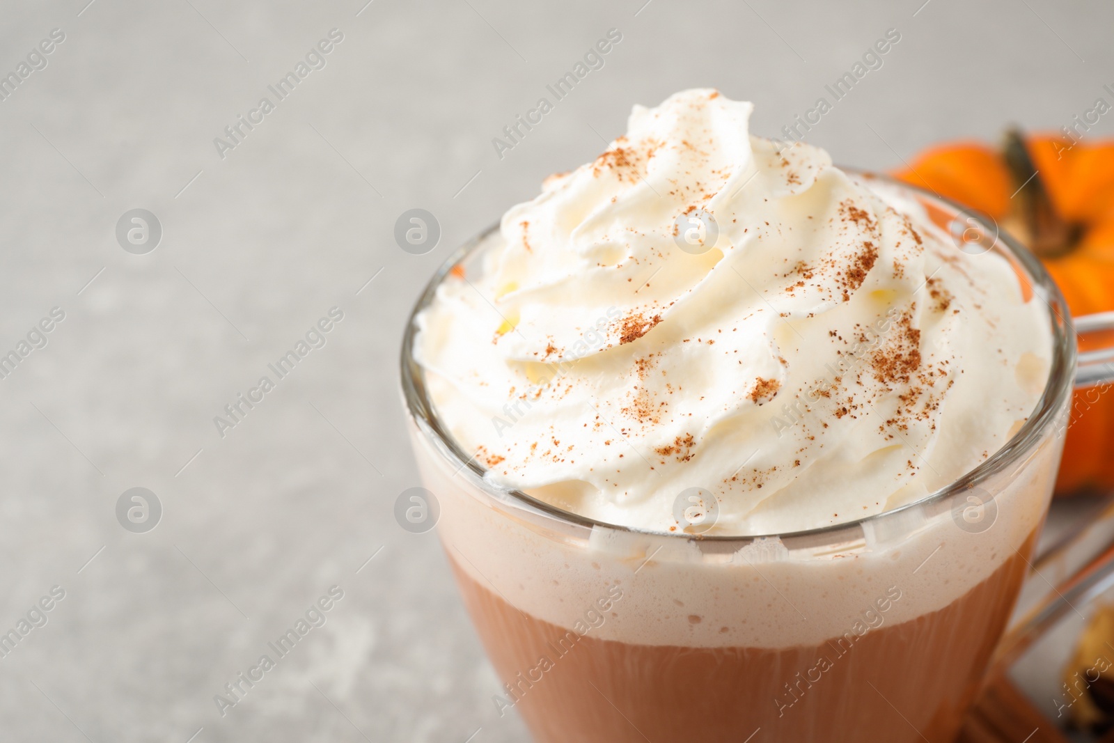 Photo of Delicious pumpkin latte on grey table, closeup