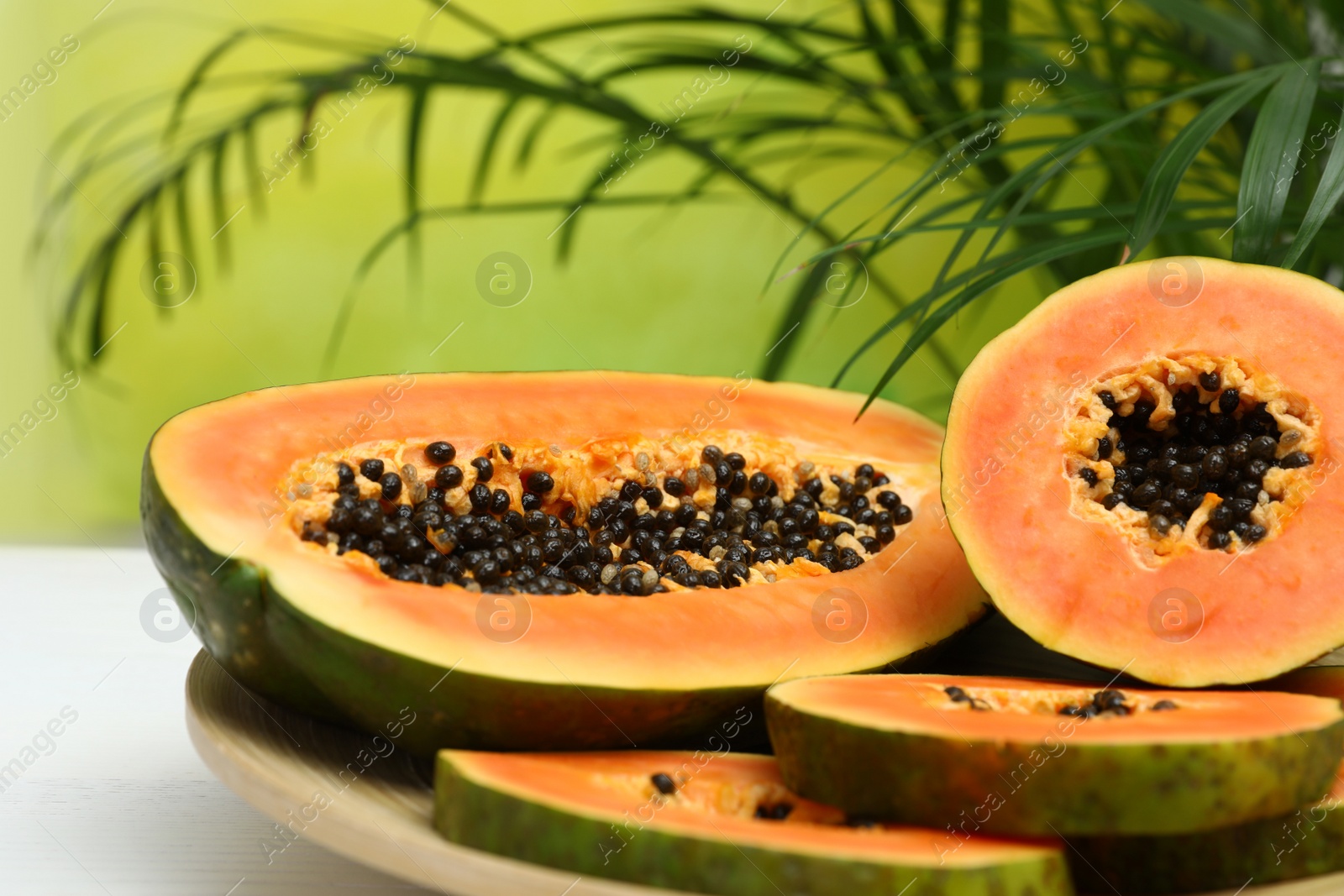 Photo of Plate with fresh juicy cut papayas on white table against blurred background, space for text